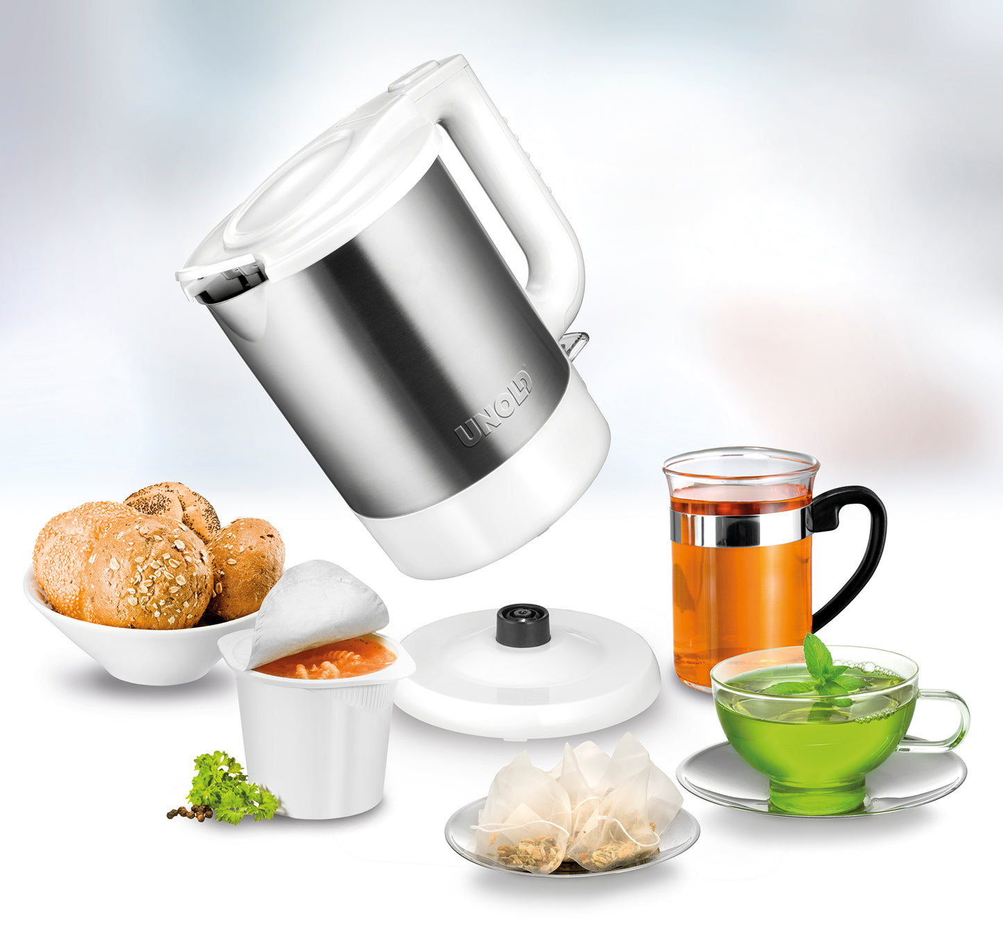 Der Edelstahl-Wasserkocher Unold Blitzkocher Edition 1,5 L übergießt neben Teebeuteln auch ein Glas Schwarztee, ein Glas Grüntee, Brötchen in einer Schüssel und einen Suppentopf mit Deckel mit heißem Wasser.