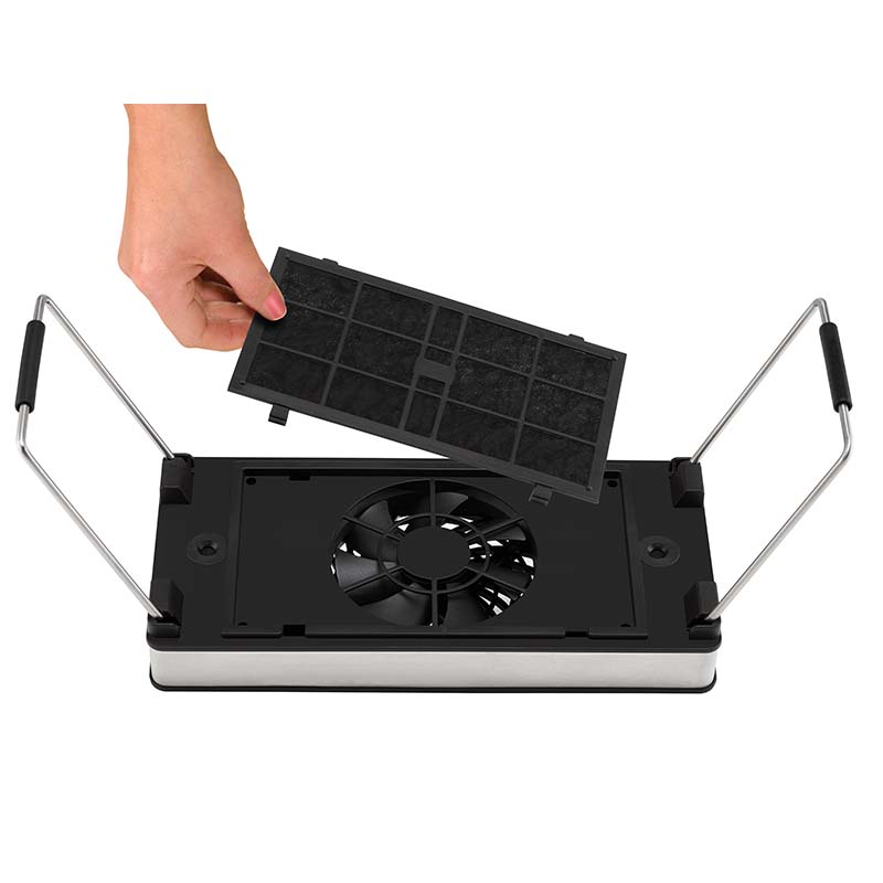 Eine Hand entfernt einen rechteckigen schwarzen Filter aus der Unold Abzugshaube Smokeless, einem kompakten Gerät mit einem zentralen Ventilator und seitlichen Metallgriffen.