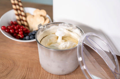Die Unold EISMASCHINE Doppio 2,4 L, gefüllt mit Vanilleeis, steht offen auf einer Holzplatte. Daneben eine Schale mit Johannisbeeren, Heidelbeeren, Keksen und Waffelröllchen.