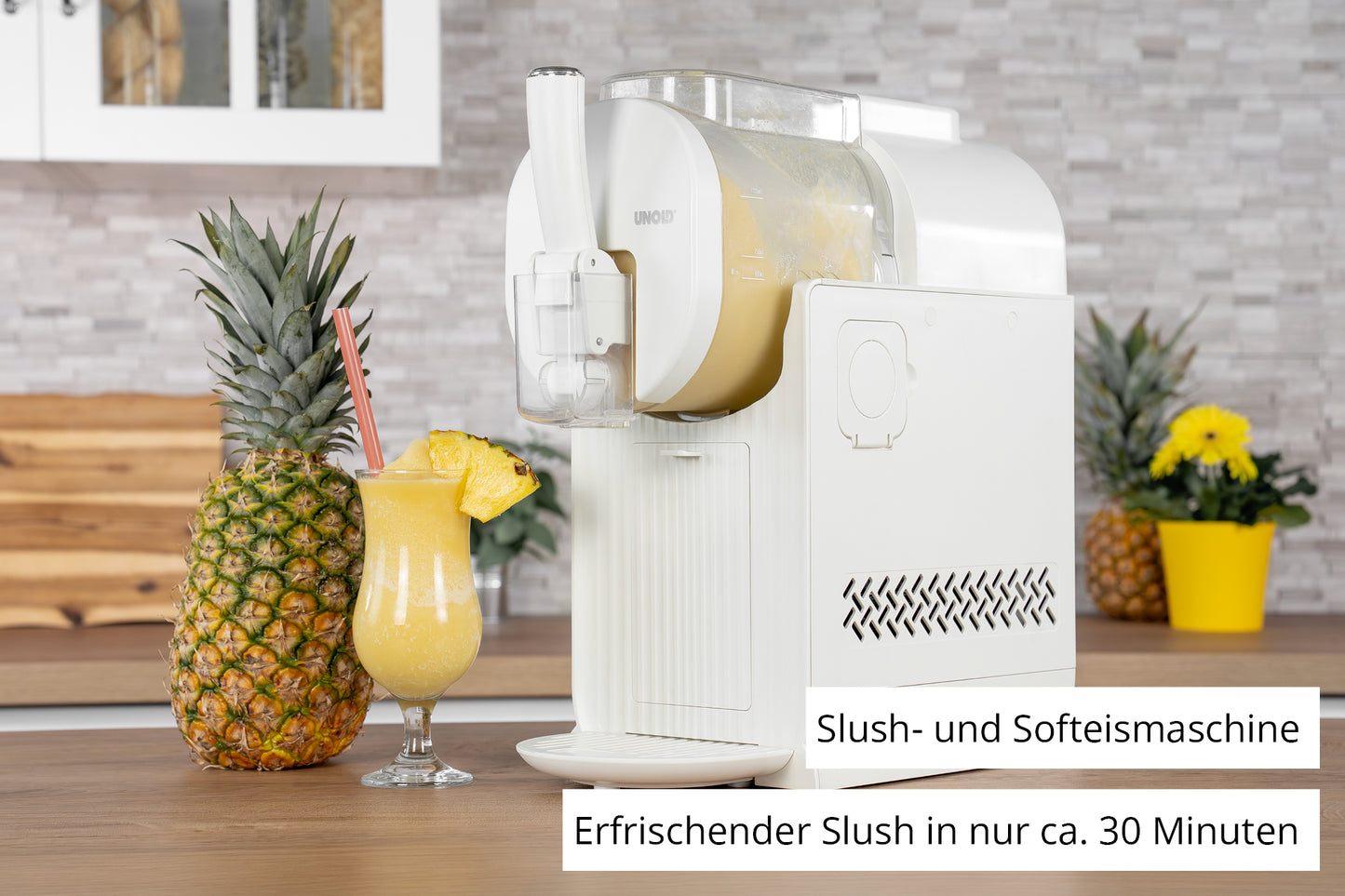 Die Unold Slusheismaschine Sofia, die auf einer Küchentheke steht, gibt gelben Slush in ein Glas mit Ananasgarnitur und frischen Ananas in der Nähe ab. Der deutsche Text hebt hervor, dass man Slush in etwa 30 Minuten herstellen kann.