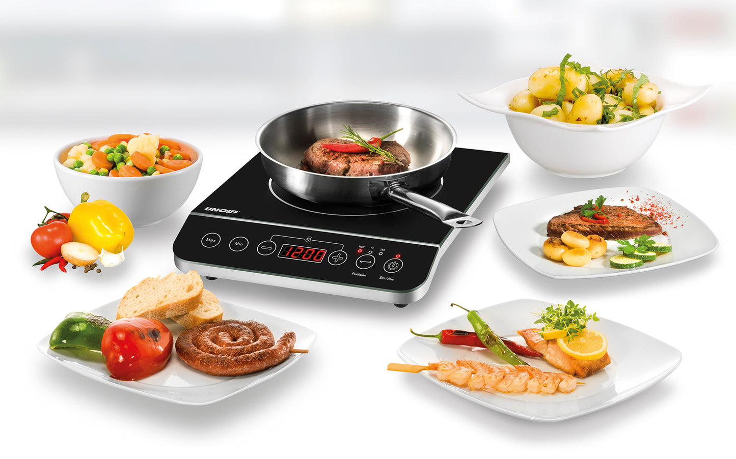 Die Unold Einzel-Induktionskochplatte - Schwarz/Edelstahl 581051 (B-Ware) der Unold AG zeigt ein gebratenes Steak in einer Pfanne, umgeben von gekochtem Gemüse, Kartoffeln, gegrilltem Fleisch, Garnelen, Brot und frischen Produkten auf einer weißen Fläche.