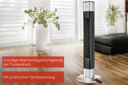 Der Unold TURMVENTILATOR EDEL in Schwarz und Silber steht auf Holzboden in einem hellen Wohnzimmer. Deutscher Text hebt 3 Geschwindigkeitsstufen und eine praktische Fernbedienung hervor, die neben dem Ventilator auf dem Boden liegt.