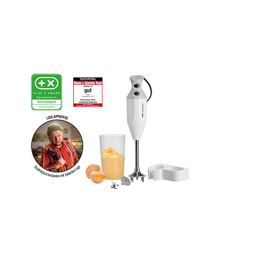 Der Stabmixer ESGE-Zauberstab® M 122 S von ESGE-Zauberstab steht aufrecht mit Aufsätzen, einem Mixbecher für Eigelb und Eierschalen, einem herzförmigen Zubehörteil und drei Prüfplaketten, darunter eine mit dem Daumen des Küchenchefs.