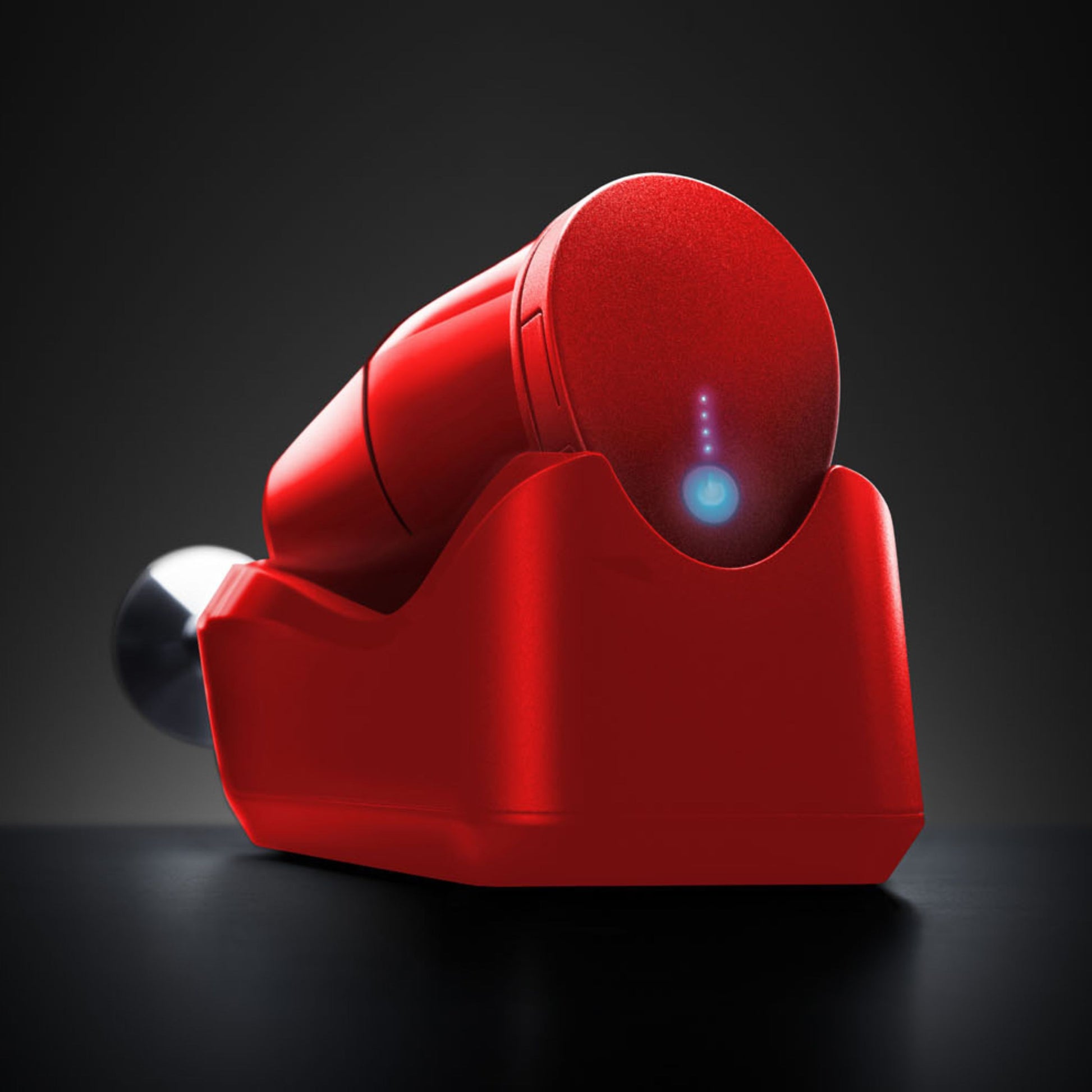 Der ESGE-Zauberstab Cordless PLUS Rot, ein elegantes, rotes, zylindrisches Gerät von ESGE-Zauberstab, verfügt über einen blau leuchtenden Einschaltknopf und ruht auf seiner passenden Ladestation vor einem dunklen Hintergrund.