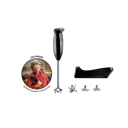 Ein kabelloser, schwarzer ESGE-Zauberstab® PRO Stabmixer mit Aufsätzen und einem Ständer, auf dem ein kreisförmiges Bild eines Kochs in einem gestreiften Hemd und einer Kochmütze zu sehen ist, auf dem auf Deutsch „Lafer Approved“ aufgedruckt ist.