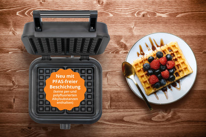 Der Unold BELGISCHES WAFFELEISEN Brüssel mit der Aufschrift "Neu mit PFAS-freier Beschichtung" ist neben einem Teller mit einer Waffel mit Beeren und einem Löffel auf einer Holzfläche abgebildet.
