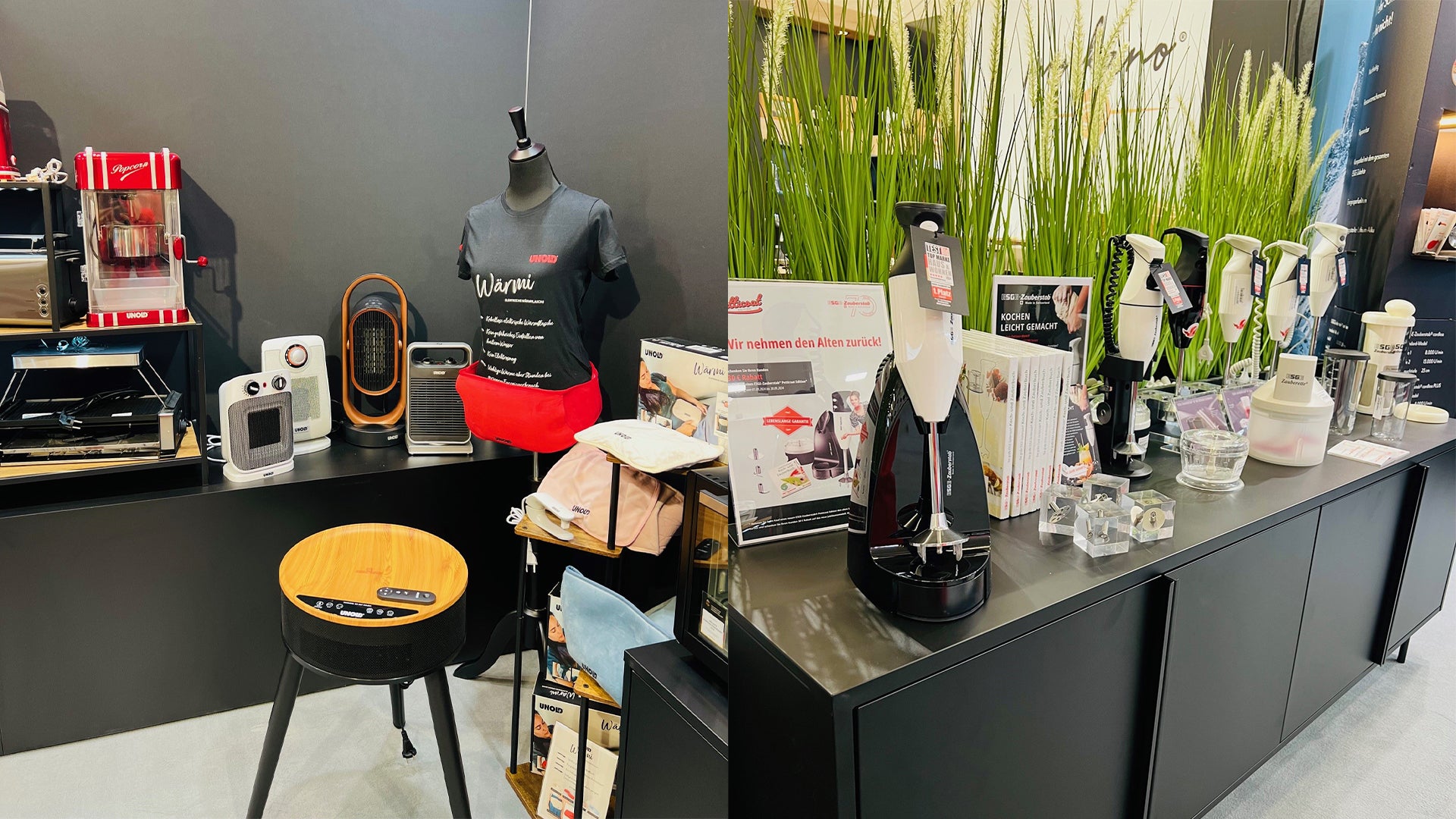 Eine Ausstellung von Haushaltsgeräten und Gadgets auf schwarzen Theken, darunter eine Schaufensterpuppe mit einer Markenschürze, ein Lautsprecher mit Holzplatte, Heizgeräte, Reinigungsgeräte und verschiedene Produktkartons, mit grünem Ziergras im Hintergrund.