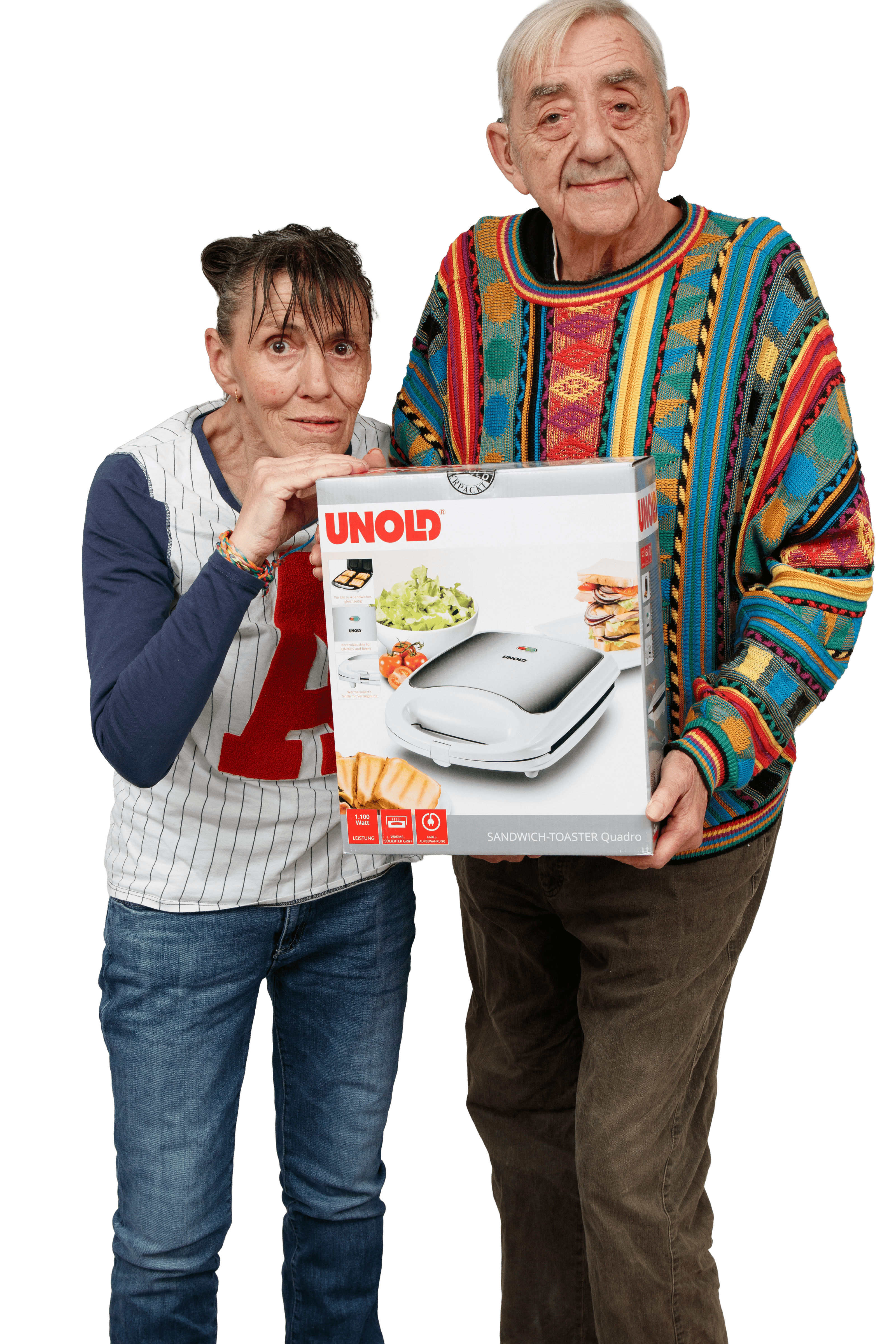 Eine ältere Frau und ein älterer Mann stehen zusammen, lächeln und halten einen verpackten UNOLD-Sandwichtoaster. Der Mann trägt einen bunten Pullover, die Frau ein weißes Hemd mit einem roten A. Der Hintergrund ist weiß.