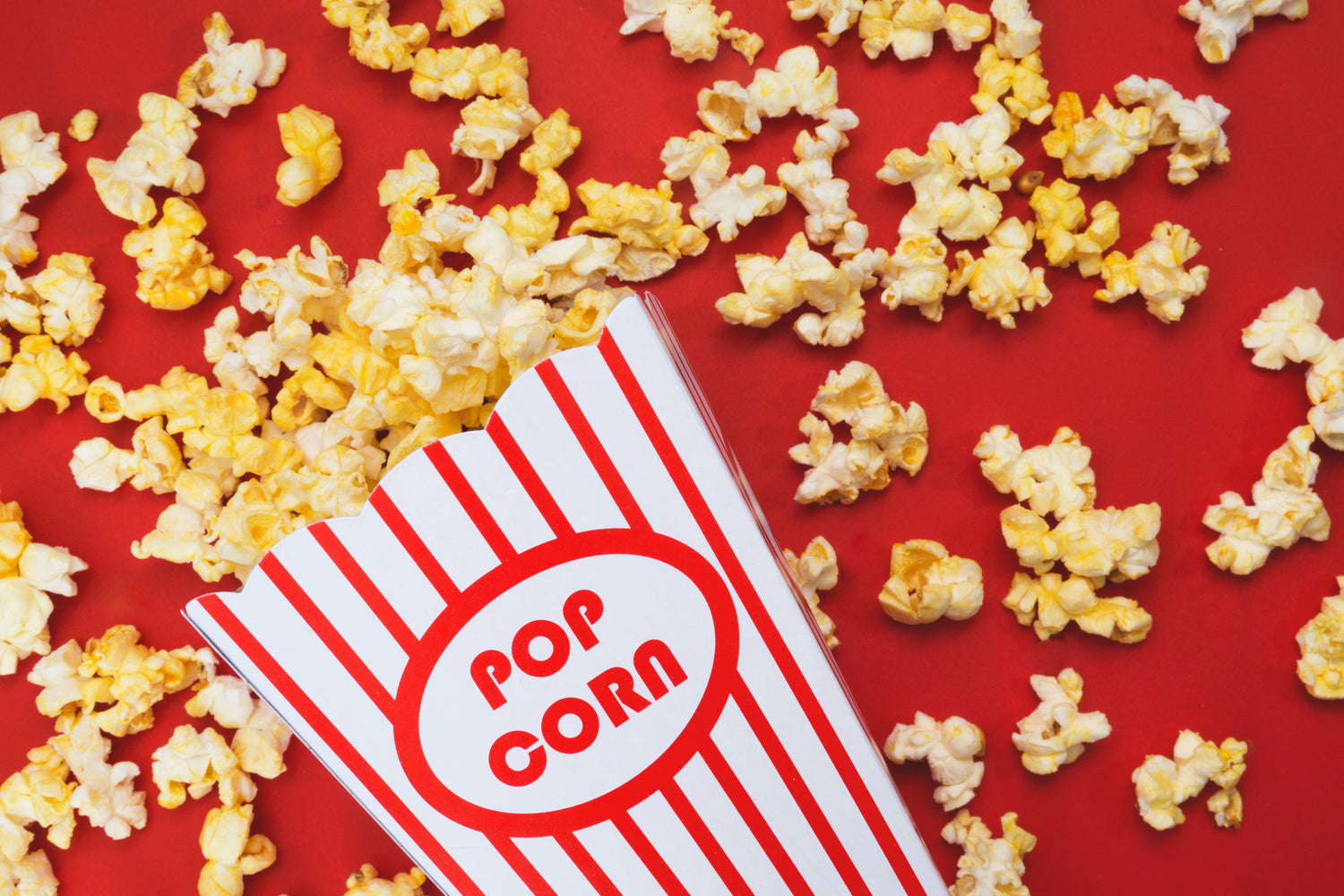 Roter Hintergrund und darauf liegen überall Popcorn stücke. 