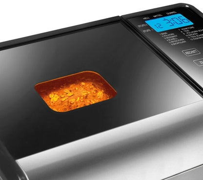 Nahaufnahme des Brotbackautomaten Unold Backmeister® Top Edition mit Digitalanzeige und Sichtfenster, durch das man den Brotteig sehen kann, der im Inneren unter warmem Licht gemischt wird.