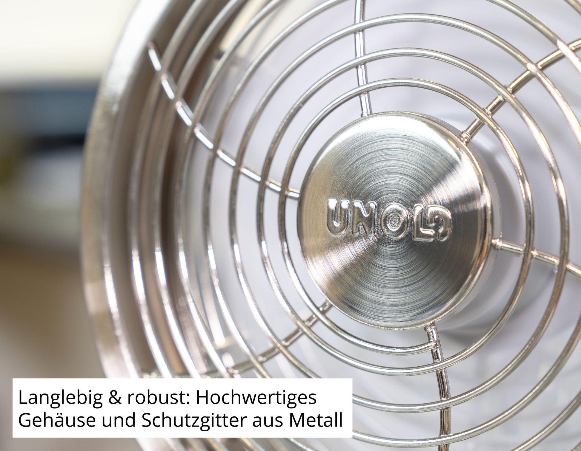 Nahaufnahme des Unold AG Akku-Tischventilator Steel Flex mit Markenname auf der Nabe. Deutscher Text: Langlebig & robust - Hochwertiges Gehäuse und Schutzgitter aus Metall.