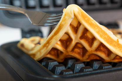 Eine Nahaufnahme einer goldenen Waffel mit knuspriger Textur und Gittermuster, die mit einer Gabel aus dem Waffeleisen „BELGISCHES WAFFELEISEN Brüssel“ von Unold gehoben wird.