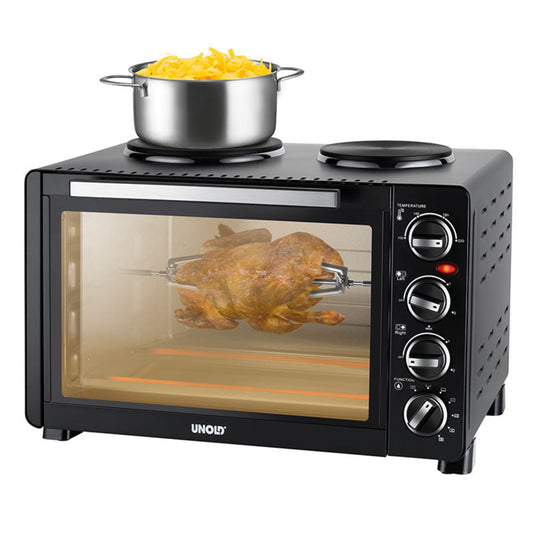 Der Unold Kleinküche All in One ist ein schwarzer Tischbackofen mit einer Glastür, Bedienknöpfen auf der rechten Seite und Platz oben für einen Topf. Hier zu sehen ist das Brathähnchen, während darüber gekochte Nudeln stehen.