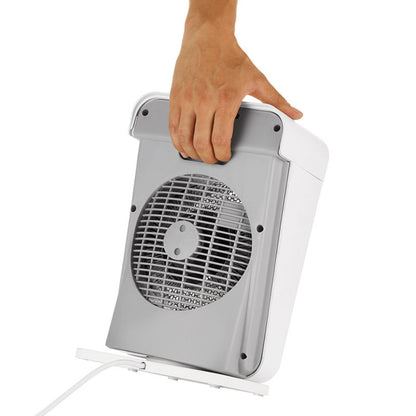 Eine Hand hebt die Unold HEIZLÜFTER BOX IP 21, einen kompakten weiß-grauen Elektrolüfter, am integrierten Tragegriff an. Das Gerät steht aufrecht, das vordere Schutzgitter und das Netzkabel sind sichtbar.